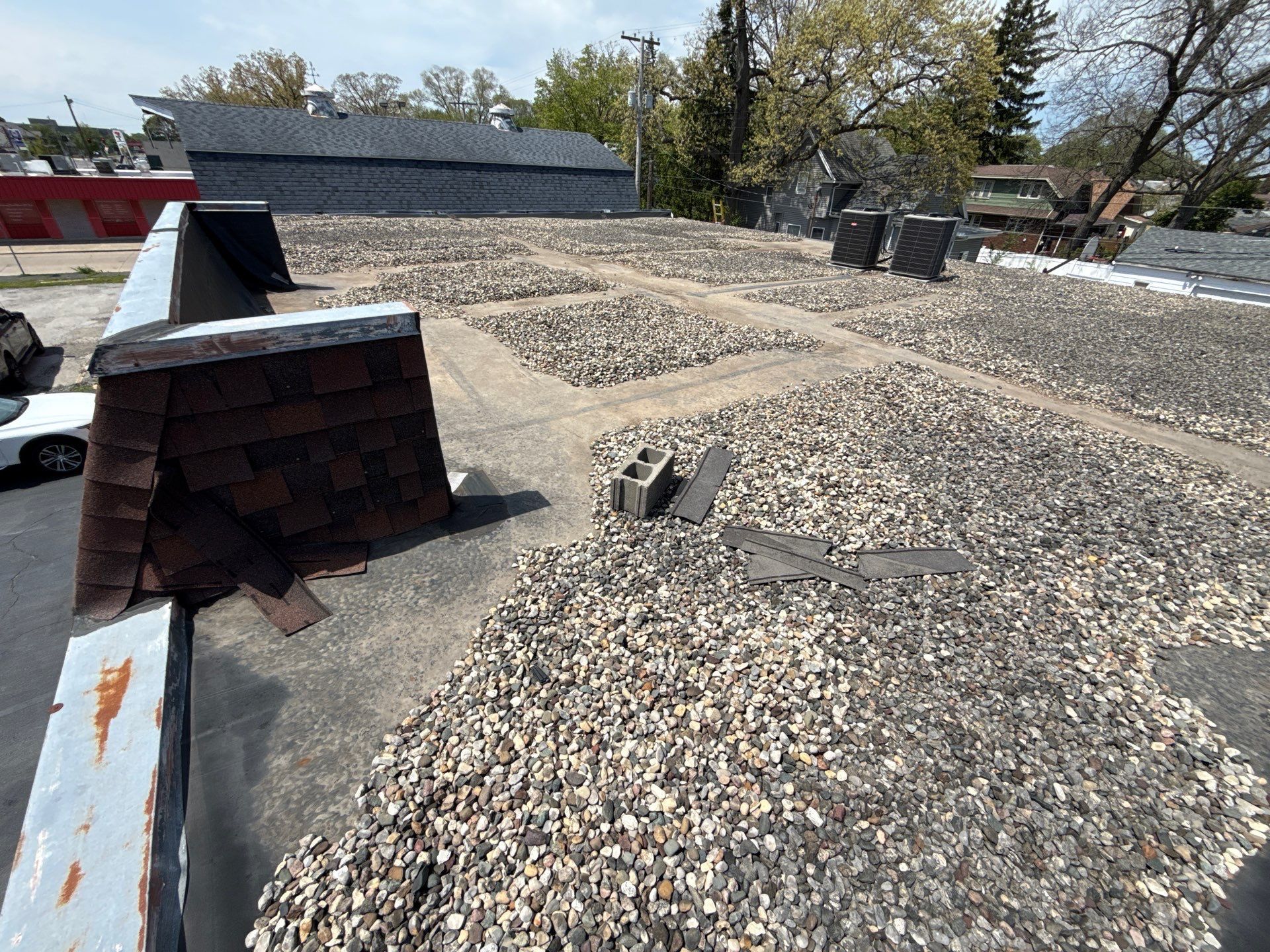 Rooftop with gravel ballast, low parapet walls, and rooftop equipment under a clear sky