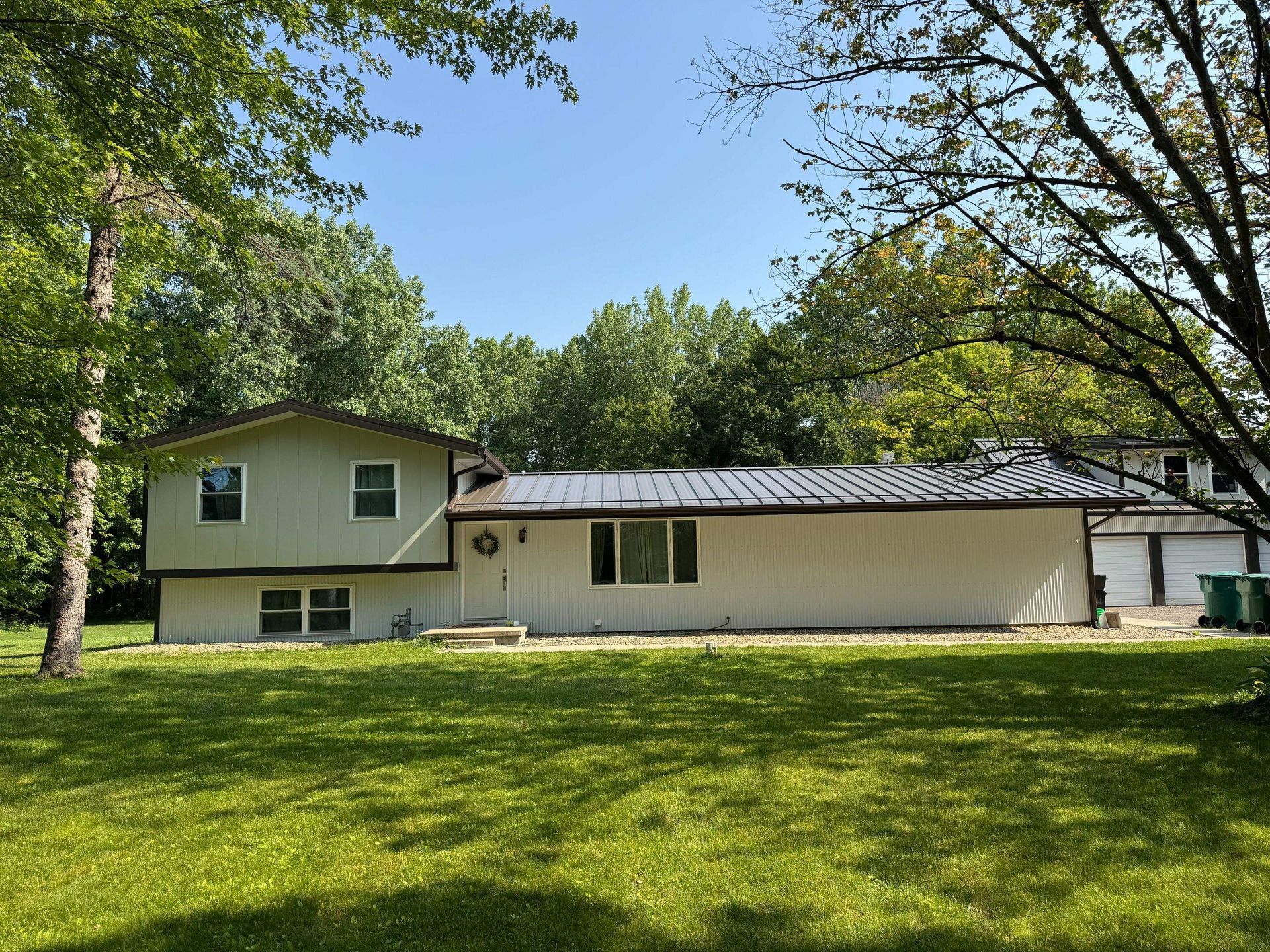 Suburban house with green lawn and trees under a clear blue sky