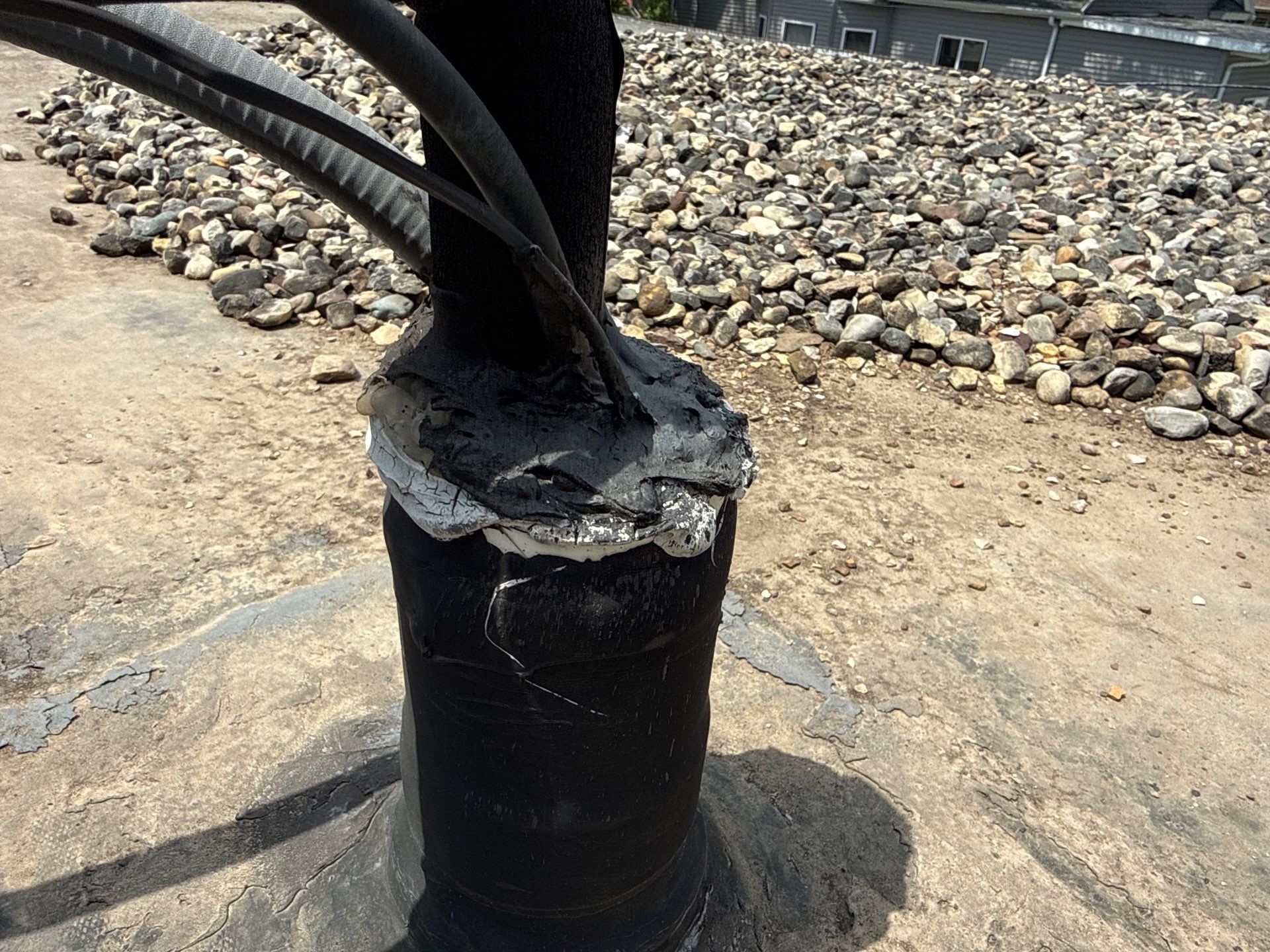 Charred utility pole base on a gravel roadside, with blackened cables rising from it