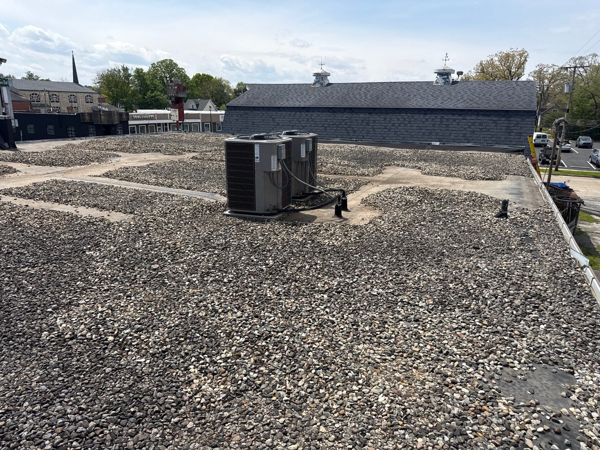 Rooftop covered in gravel with HVAC units and low buildings in the background
