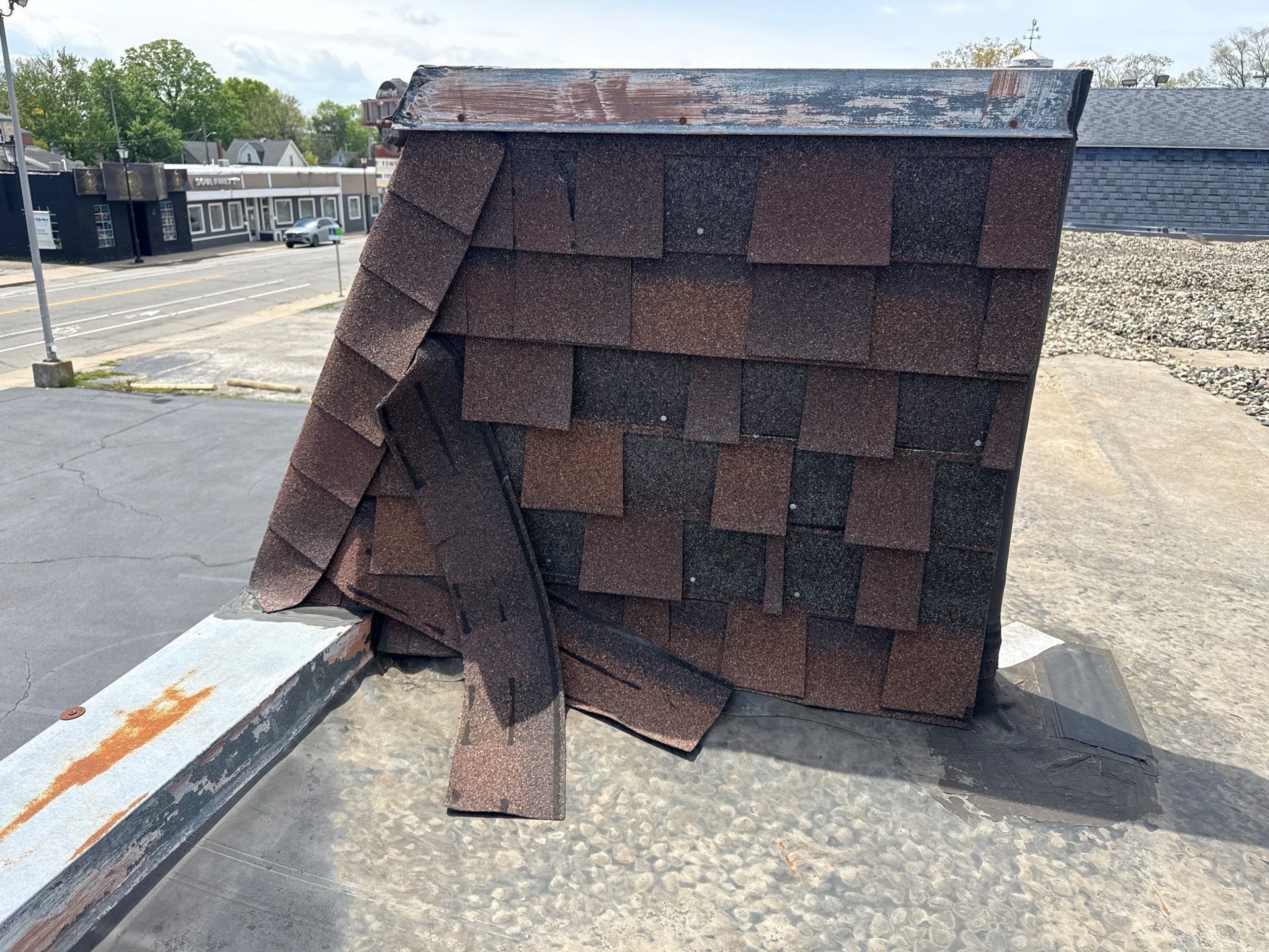 Collapsed roof shingles stacked on a concrete surface outdoors