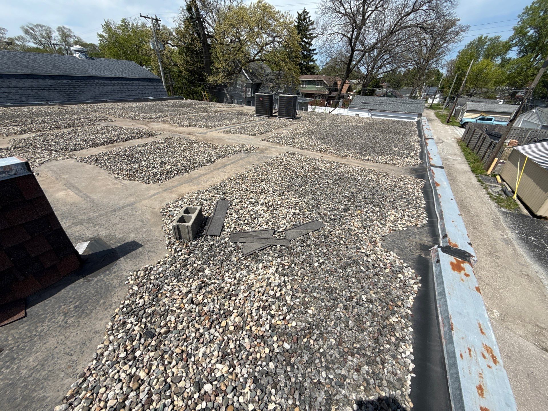 Rooftop covered with white gravel, blue-edged parapet, and HVAC equipment under a clear sky