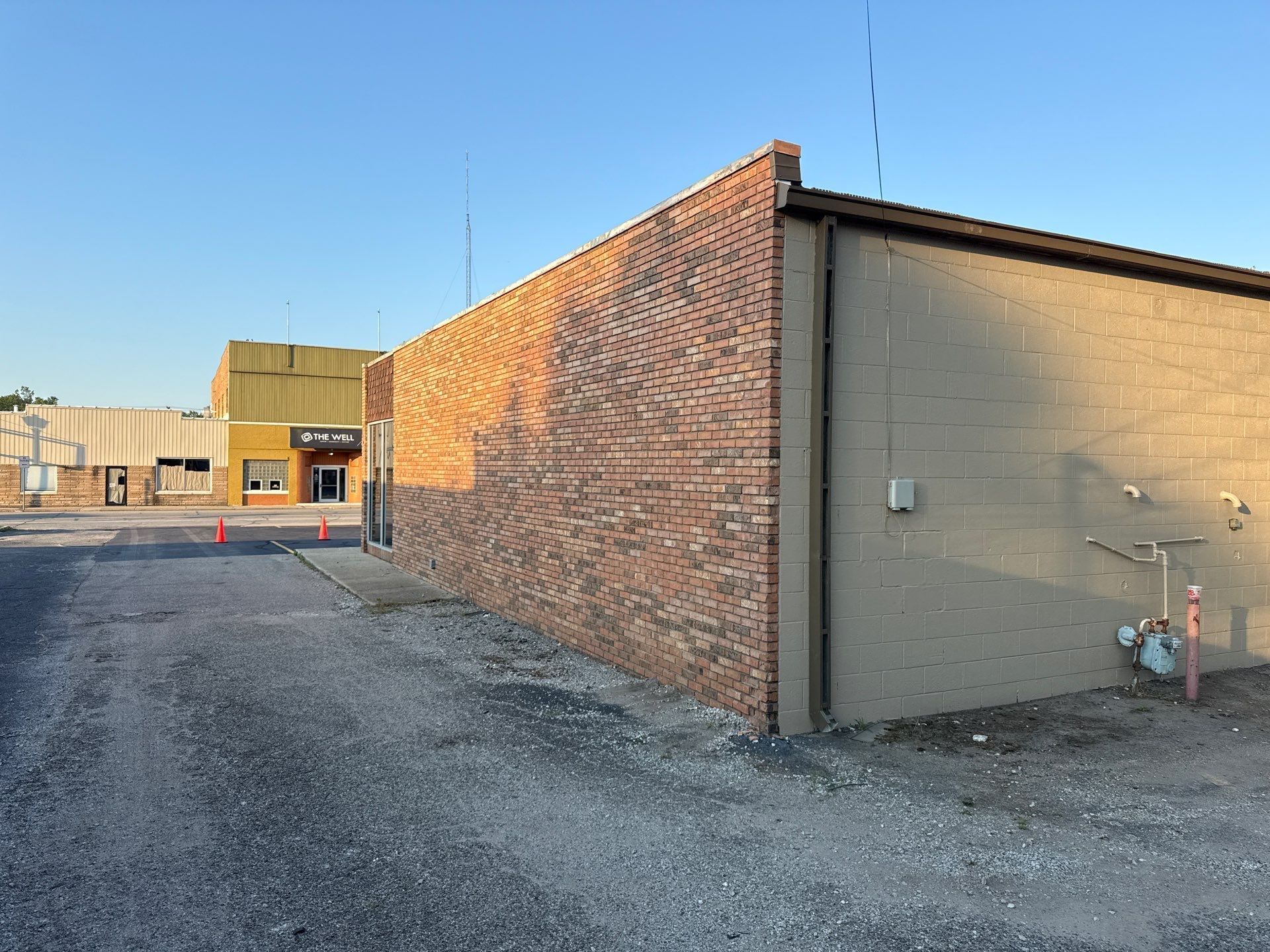 Brick industrial building corner with gravel lot and clear blue sky