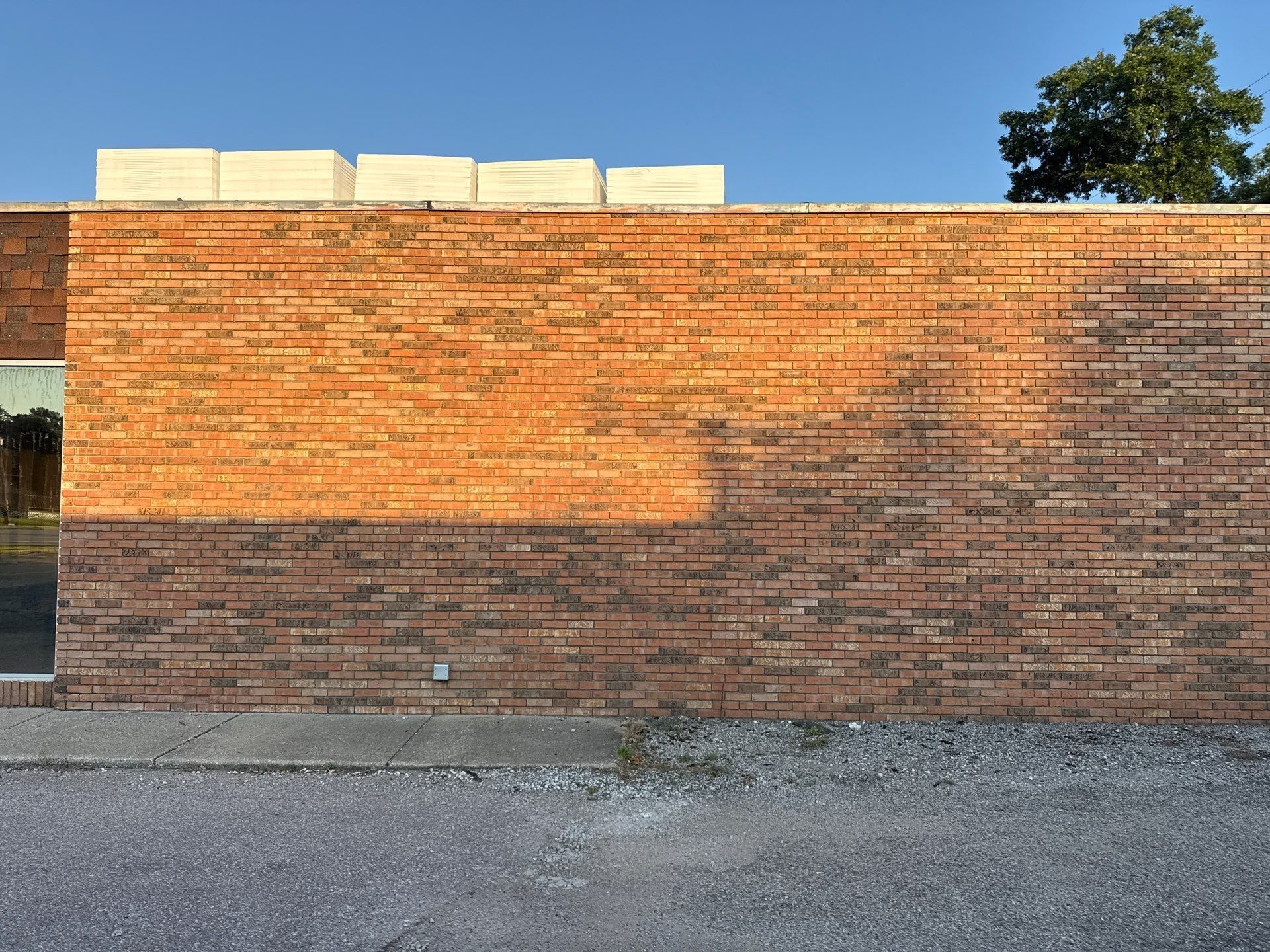Sunlit brick wall with a gravel foreground under a blue sky