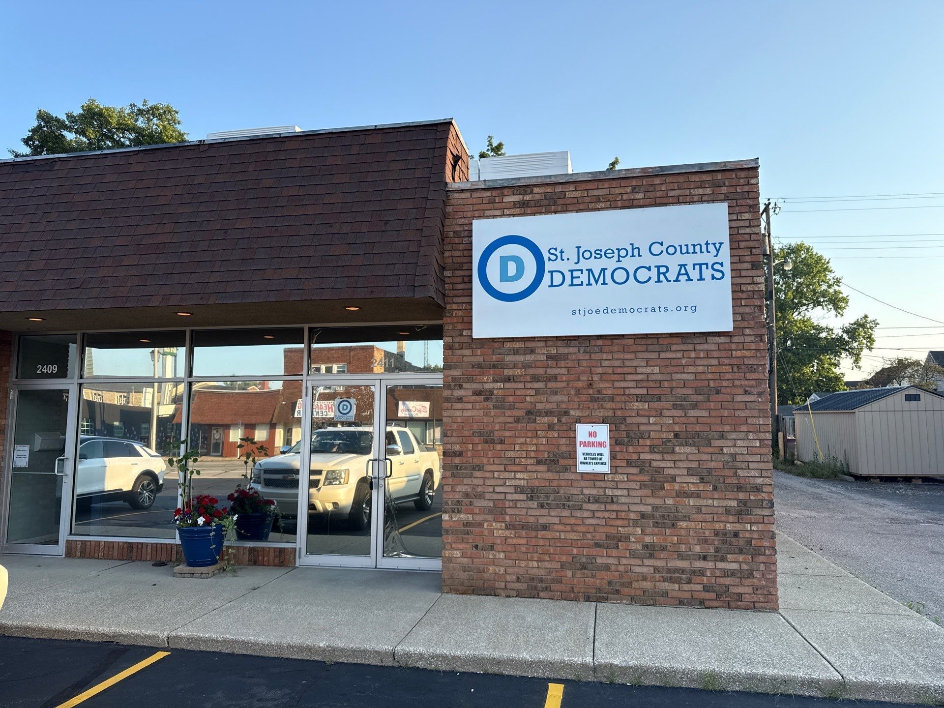 Exterior of a brick dental clinic with large windows and a blue-and-white sign.