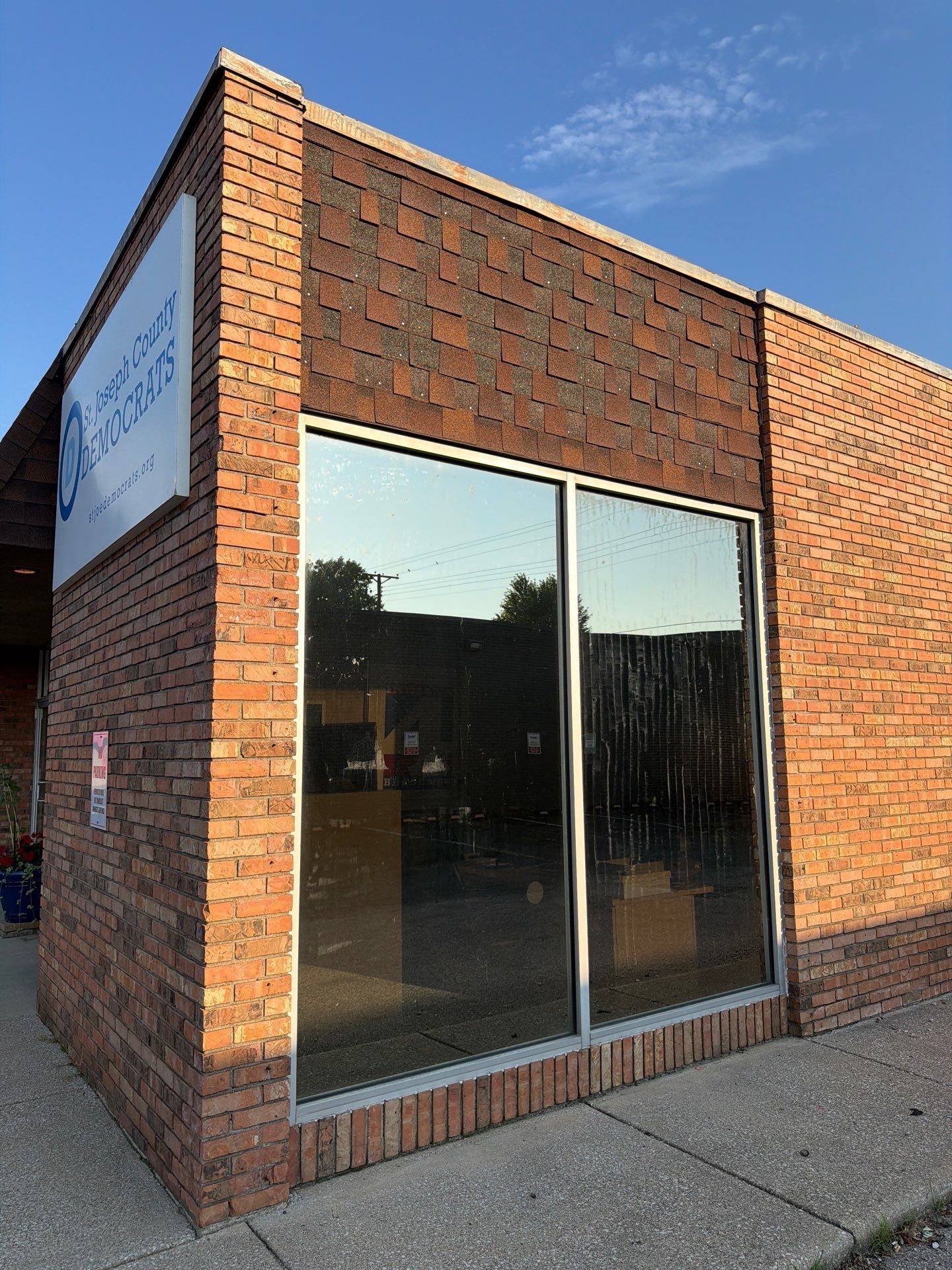 Brick storefront with large reflective glass windows on a sidewalk corner