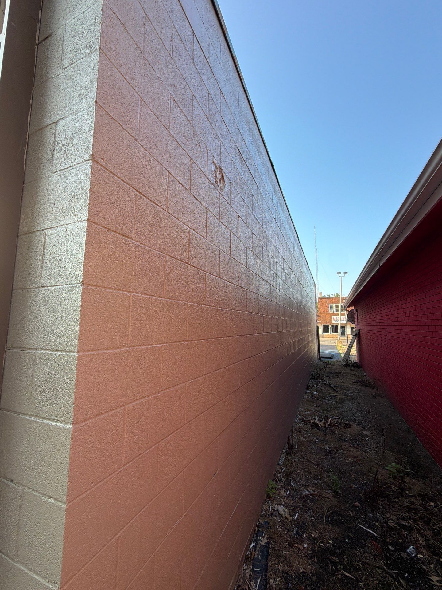 Narrow passage between orange and red walls with a dirt path and blue sky overhead