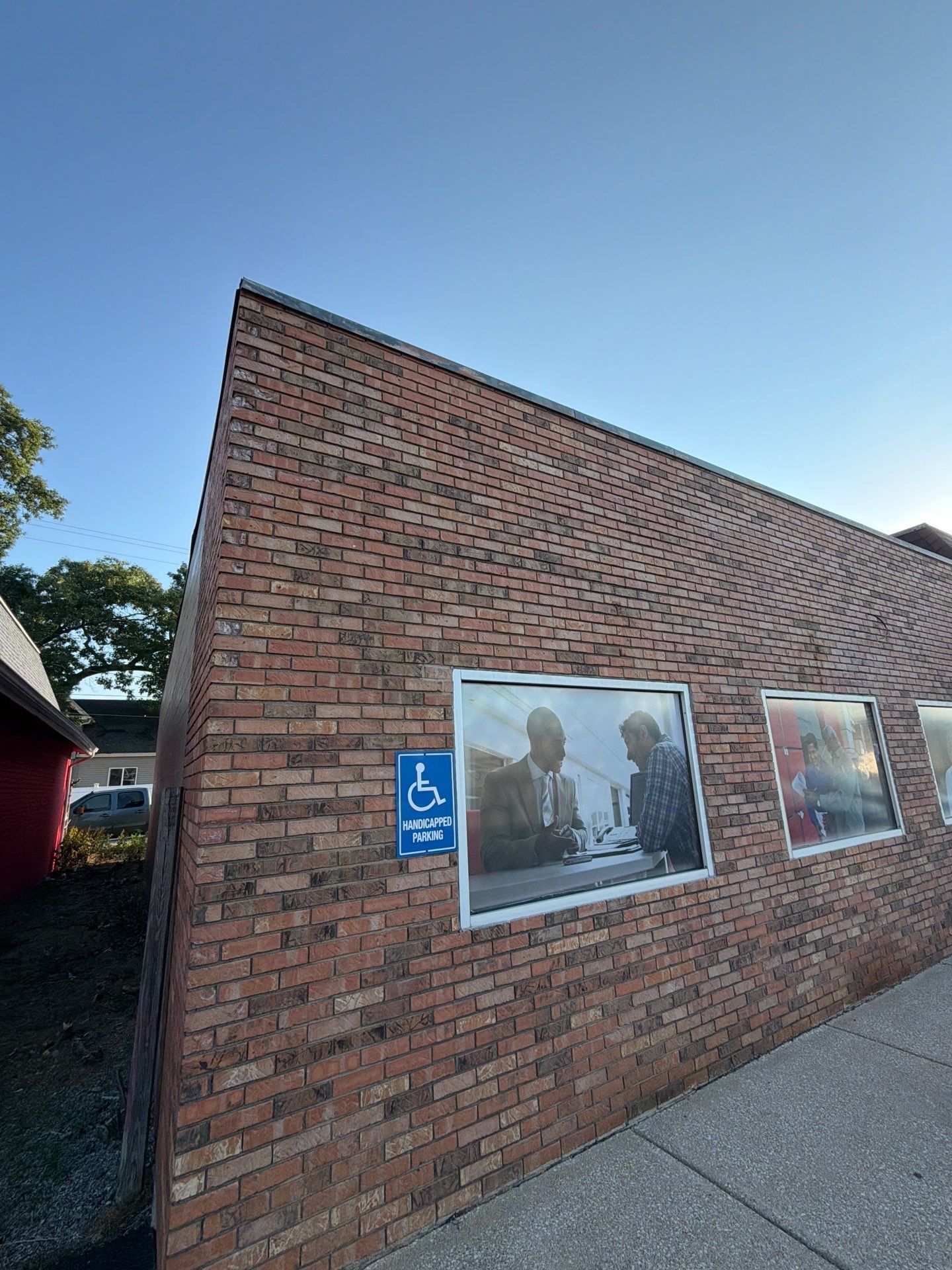 Brick wall with commemorative photo panels and an accessibility sign under a blue sky
