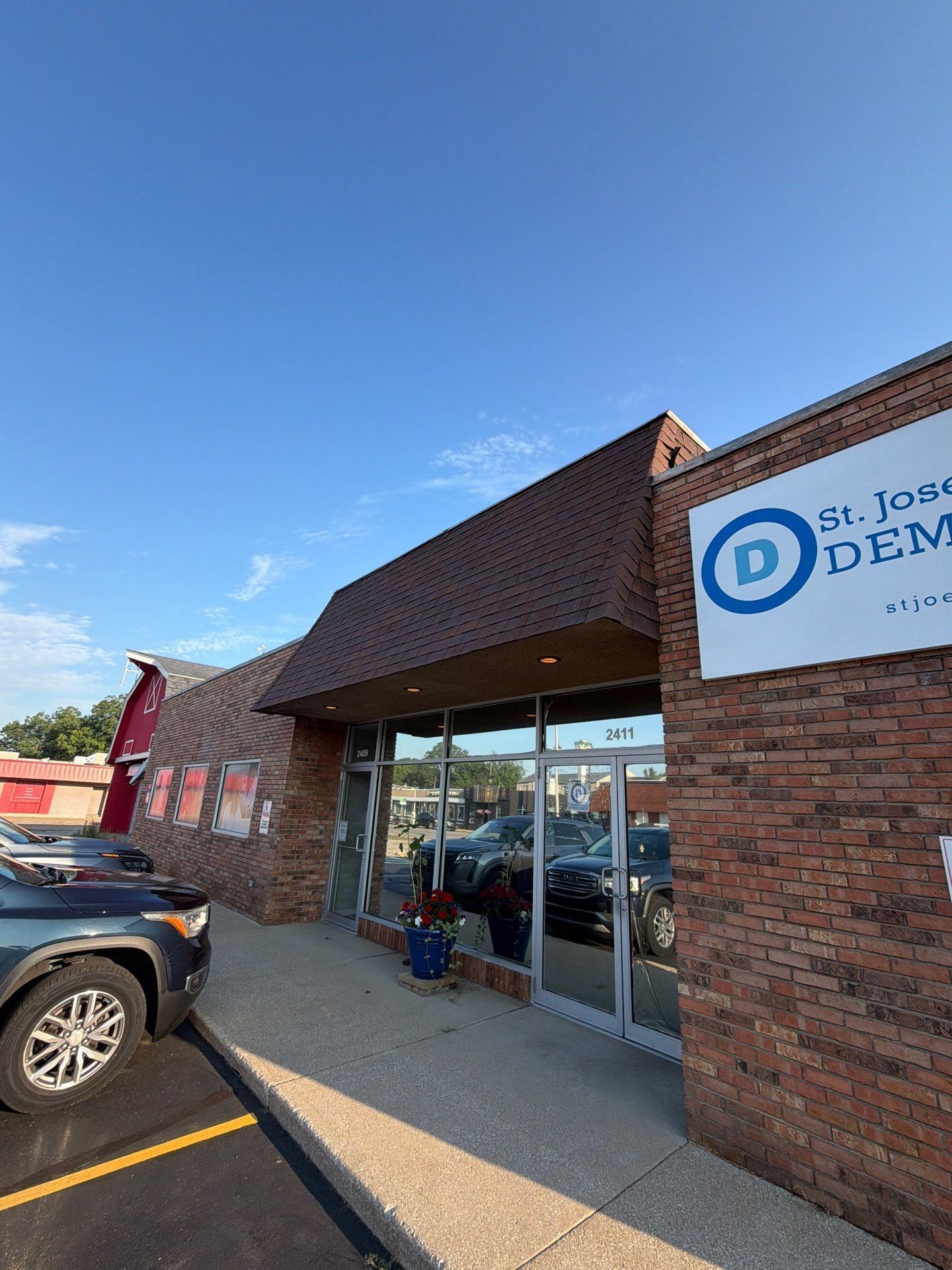 St. John Dental storefront with brick facade, glass entrance, and parked cars on a sunny day