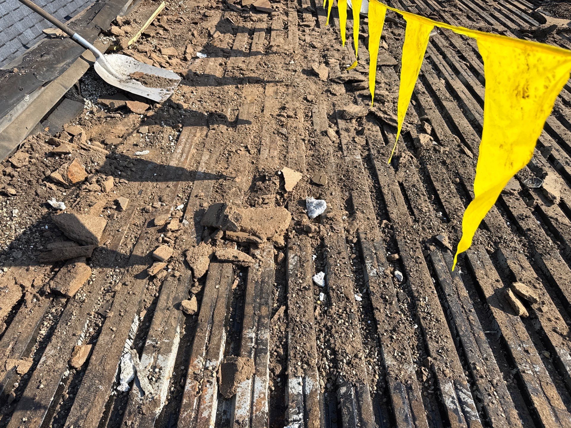 Construction trench with exposed wooden slats and yellow caution tape along the right side.