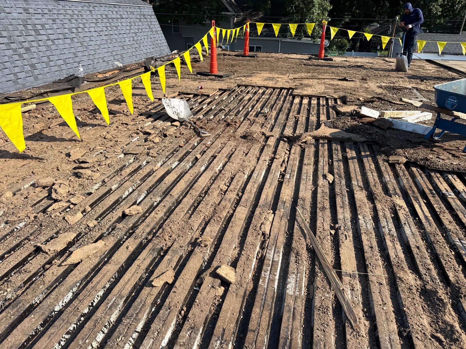 Construction site with muddy ground, yellow caution flags, and workers in the background