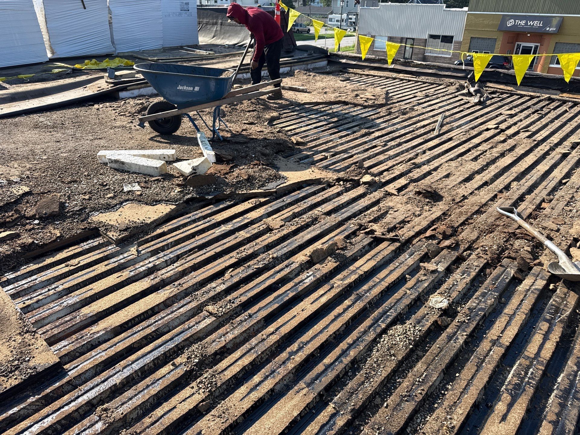Construction site with rebar grid and two workers near yellow barriers in bright sunlight