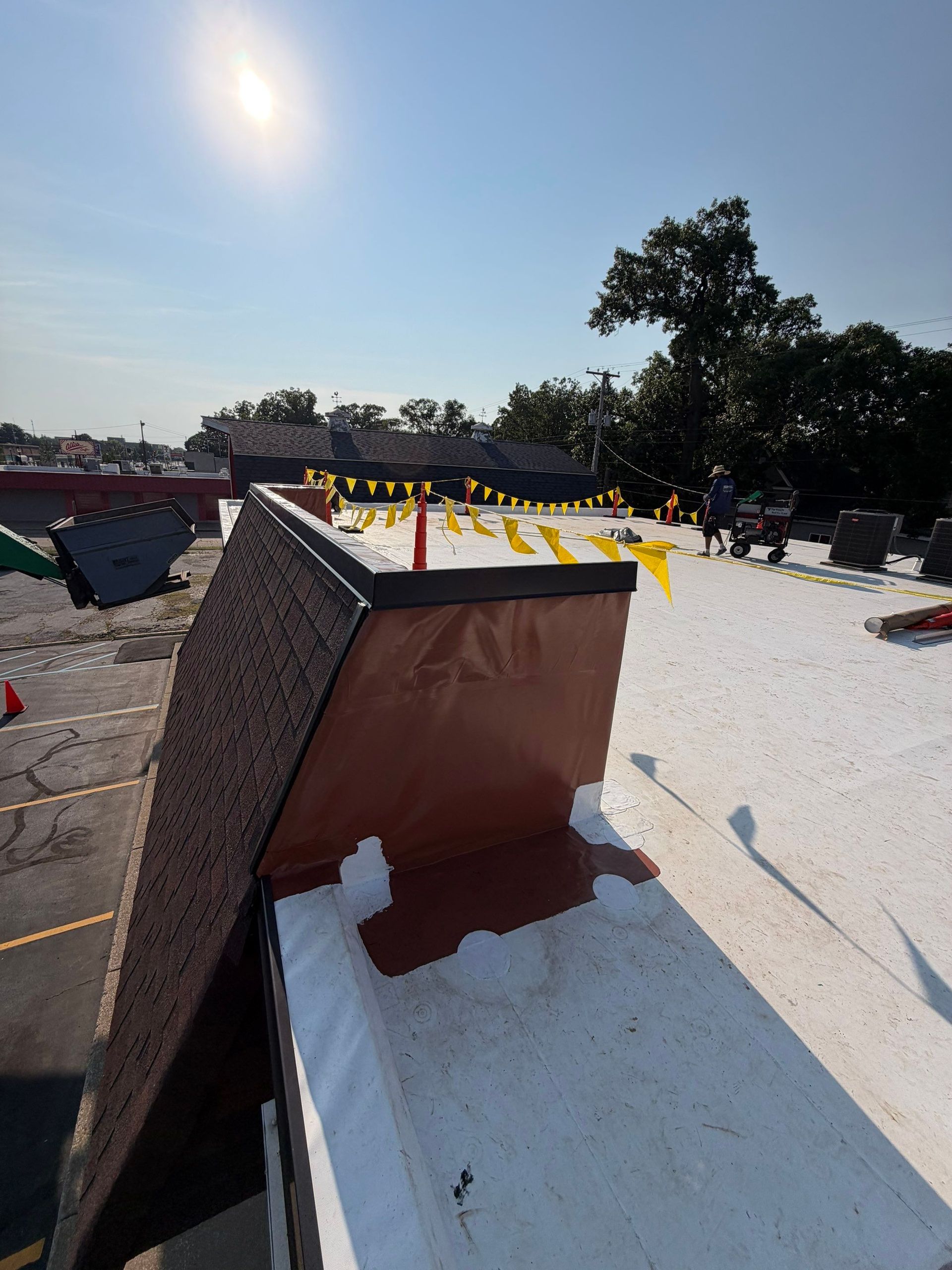 Rooftop with white coating, a small brown structure, and yellow caution tape under a bright sun