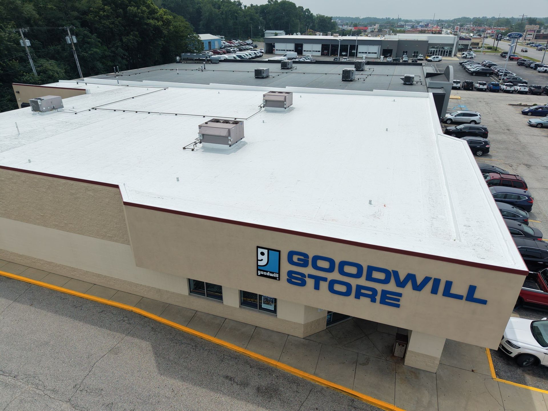 Aerial view of a Goodwill store with a white roof and parking lot around it.