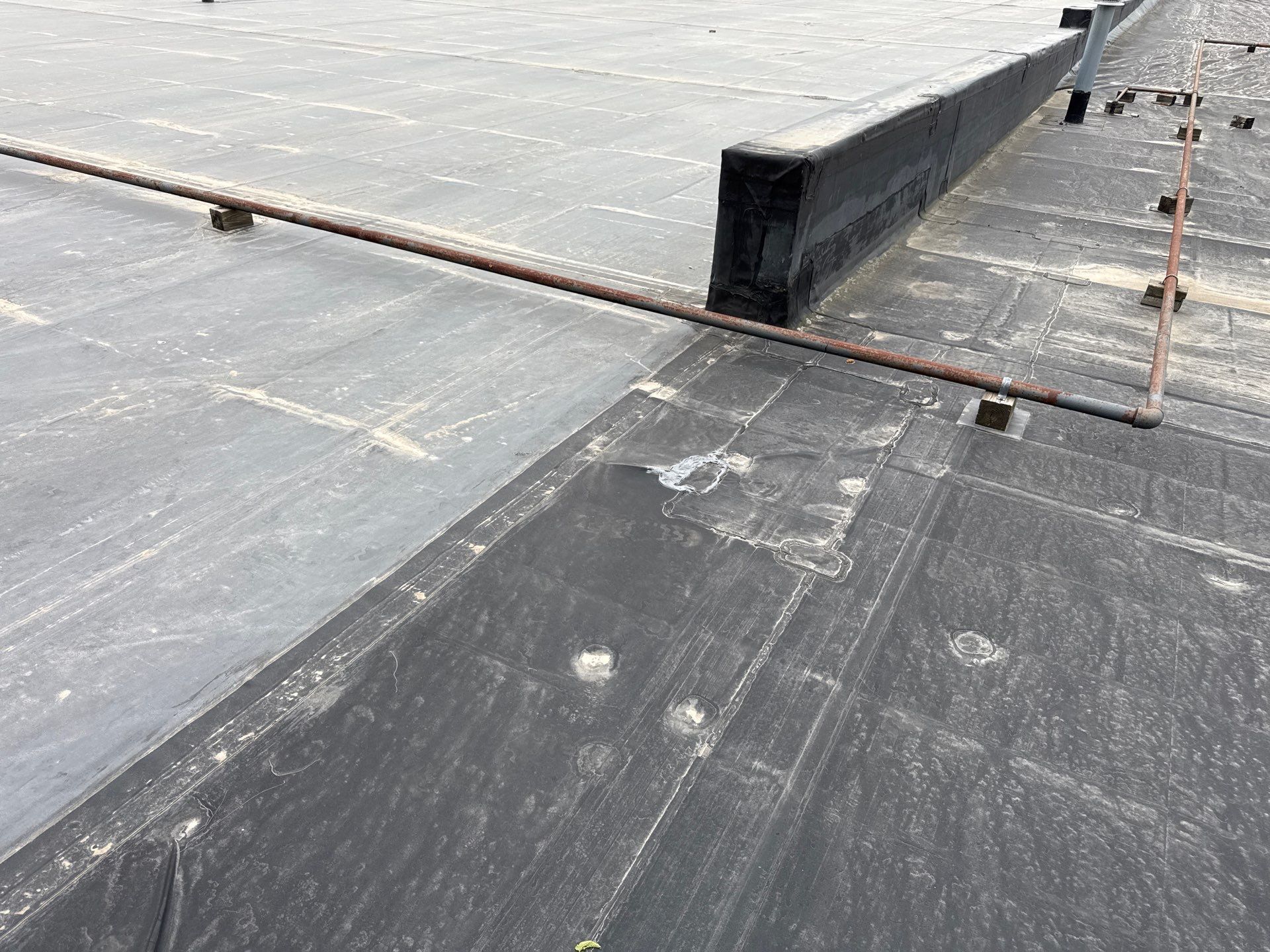 Rooftop with black membrane, a raised vent barrier, and a seam line across the surface