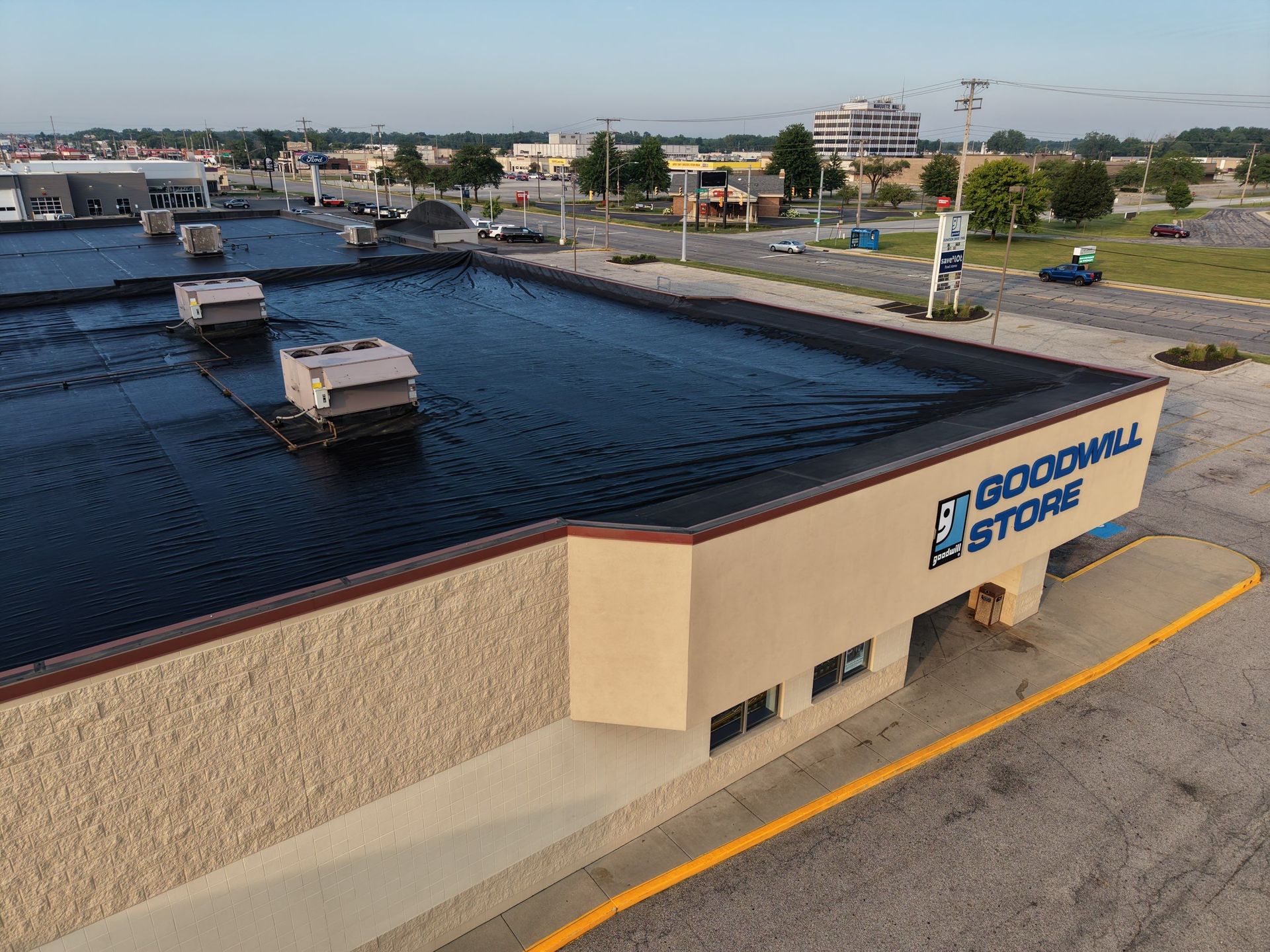 Canal-side building with blue sign and rooftop view over dark water and docked boats