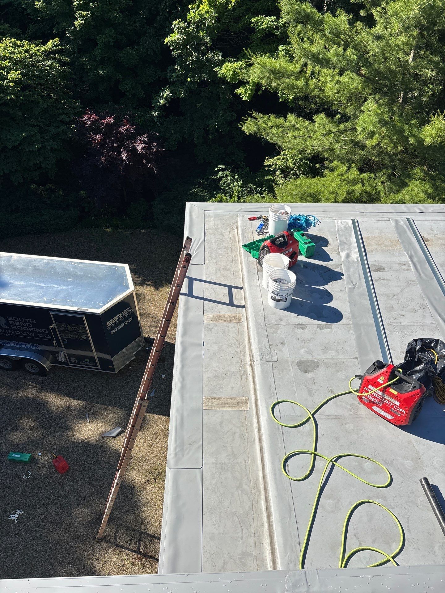 Kids playing on a rooftop deck with a toy truck, toy figures, and a red bag near trees below
