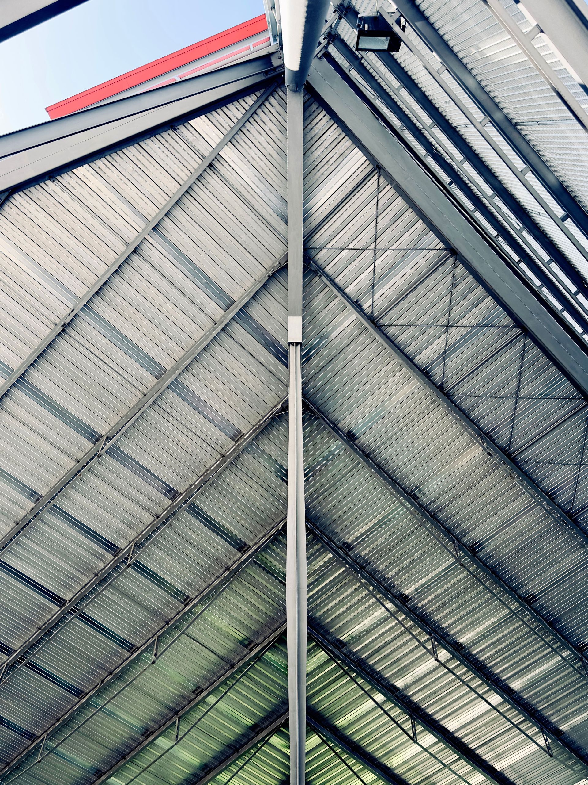 Diagonal view of a glass-and-metal building facade with geometric lines and blue-red accents