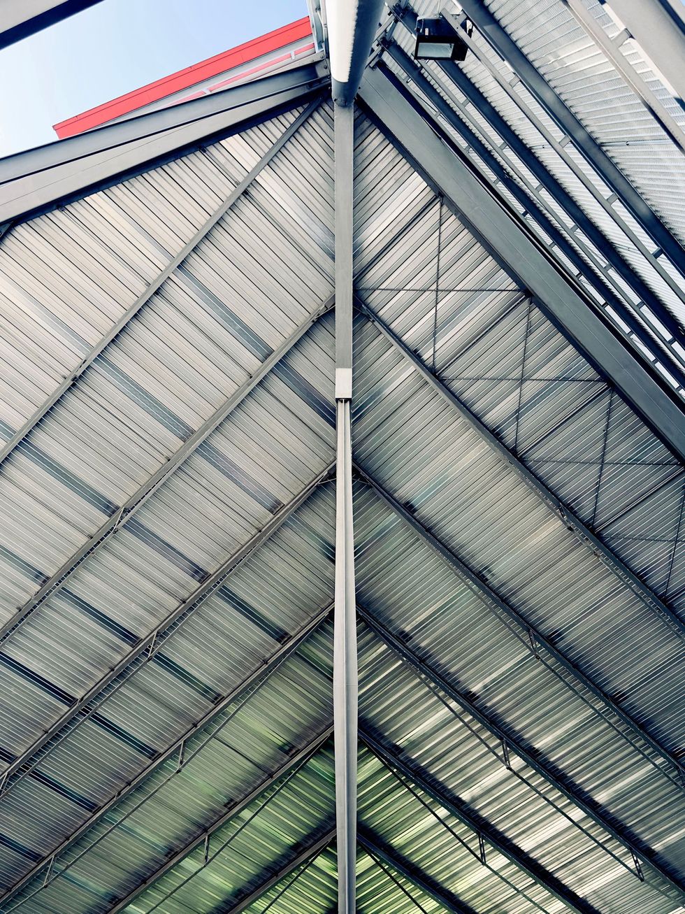 Abstract view of a metal and glass roof structure with diagonal beams and colorful reflections