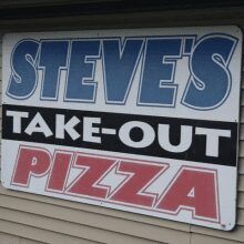 A sign against beige siding reads 
