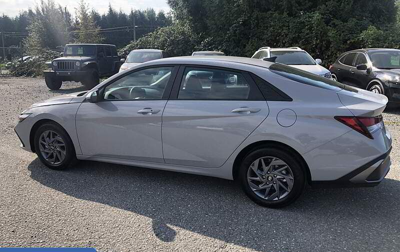 Gray Hyundai sedan parked on gravel. Other vehicles and trees in background.