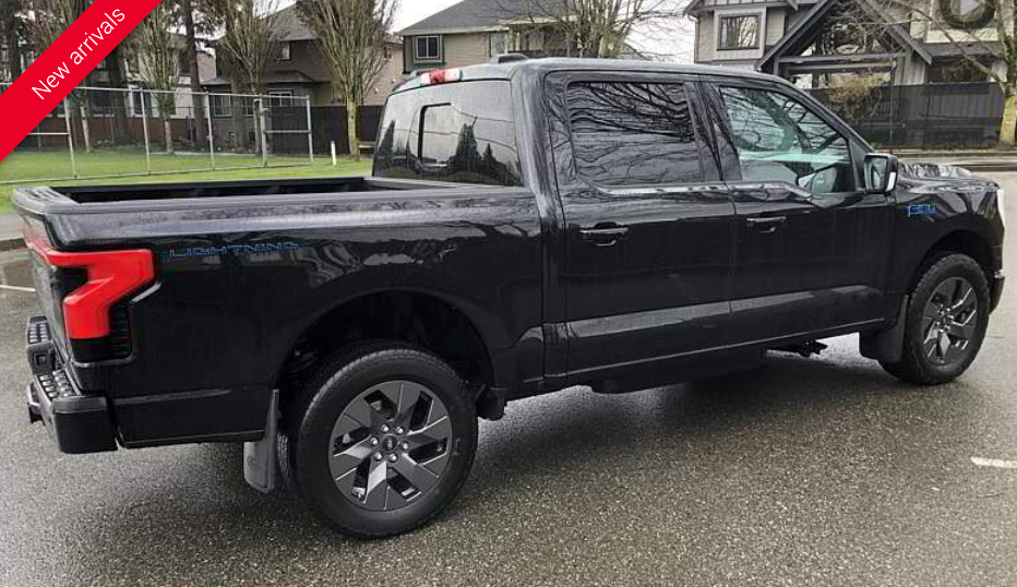 Black Ford F-150 Lightning pickup truck parked on wet pavement. Red 
