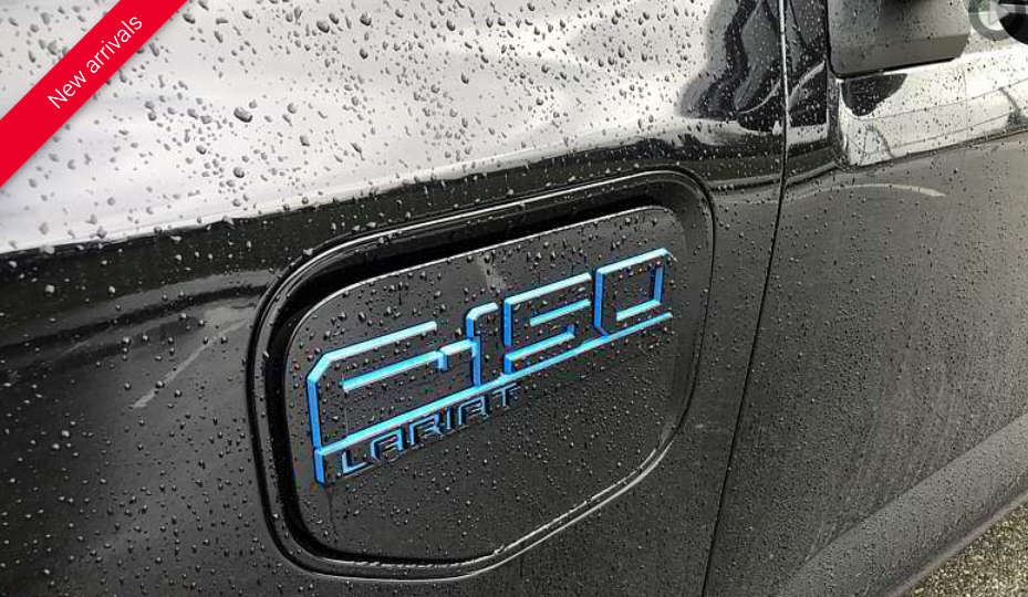 Close-up of a black Ford F-150 Lightning's charging port door, with blue 