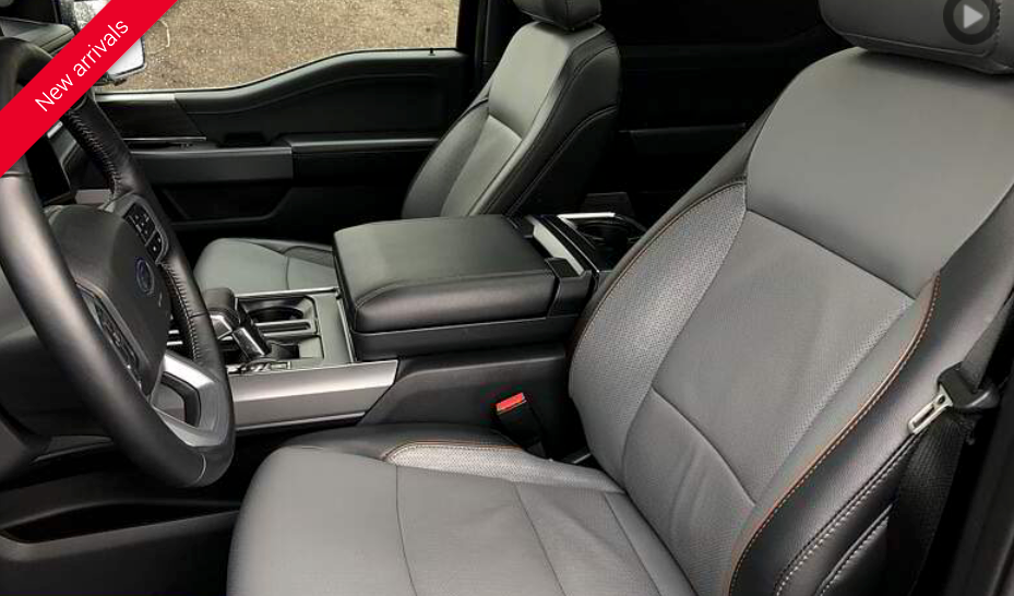 Gray and black leather interior of a vehicle, including seats, console, and steering wheel.