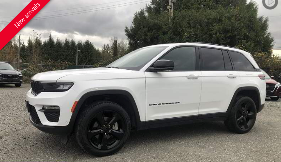 White Jeep Grand Cherokee SUV with black wheels, parked outdoors.