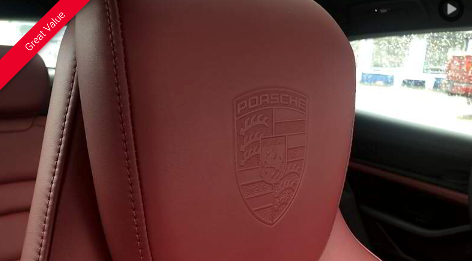 Red leather car seat with embossed Porsche emblem.