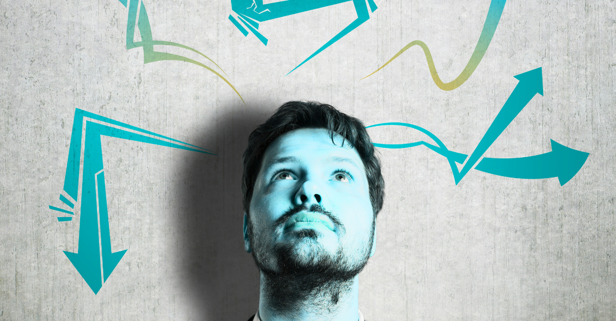 Man looking up at teal arrows and lines against a gray wall, suggesting multiple directions and choices.