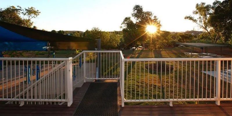 The Sun Is Setting Behind A White Railing On A Deck — Leichhardt Accommodation in Mornington, QLD