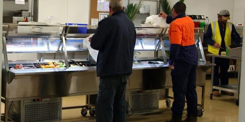 Two Men Are Standing In Front Of A Buffet Line In A Kitchen — Leichhardt Accommodation in Mornington, QLD