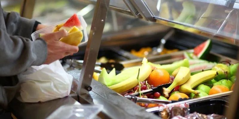 A Person Is Taking A Sandwich From A Buffet Line Filled With Fruit — Leichhardt Accommodation in Mornington, QLD