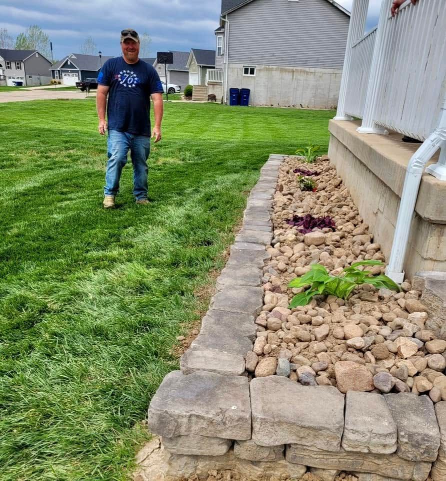 Man standing on a lawn beside a rock garden and house wall on a suburban property
