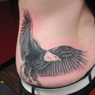 A woman has a tattoo of an eagle on her stomach