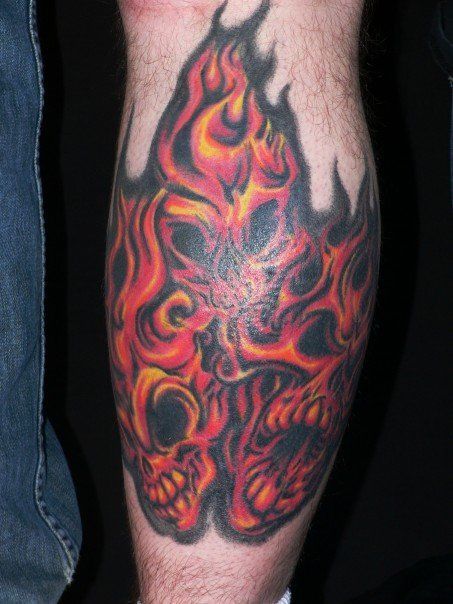 A man has a tattoo of a skull with flames on his leg.