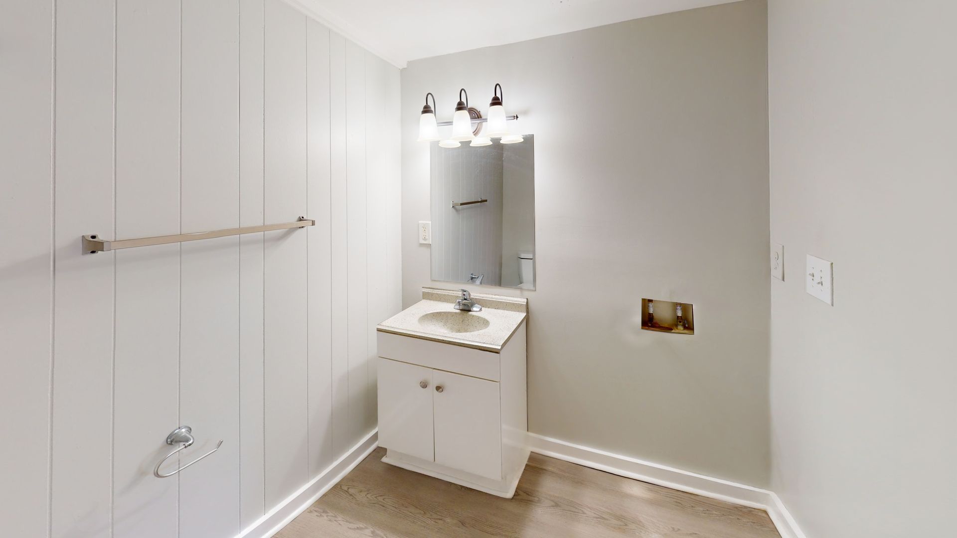 Small white bathroom with built-in cabinets, vanity, mirror, and beige tile floor.