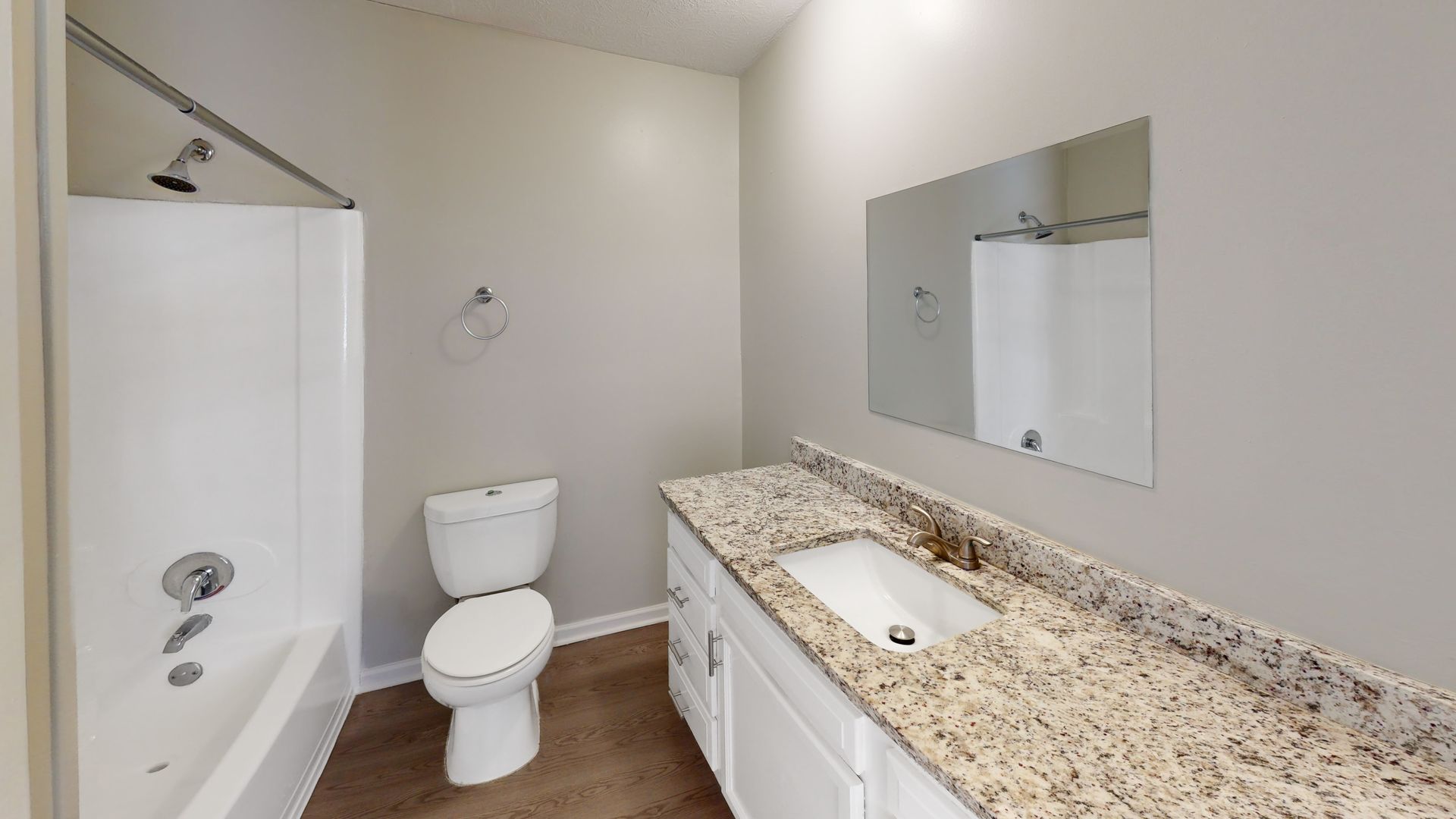 Bright bathroom with bathtub, toilet, vanity with granite countertop, and wall mirror