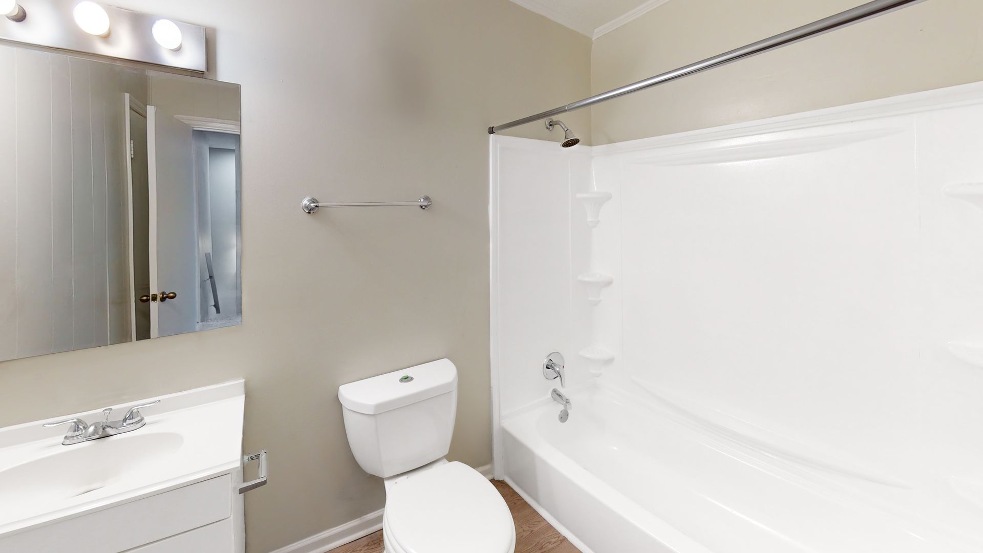 Bright bathroom with vanity, mirror, toilet, and white bathtub with shower curtain.
