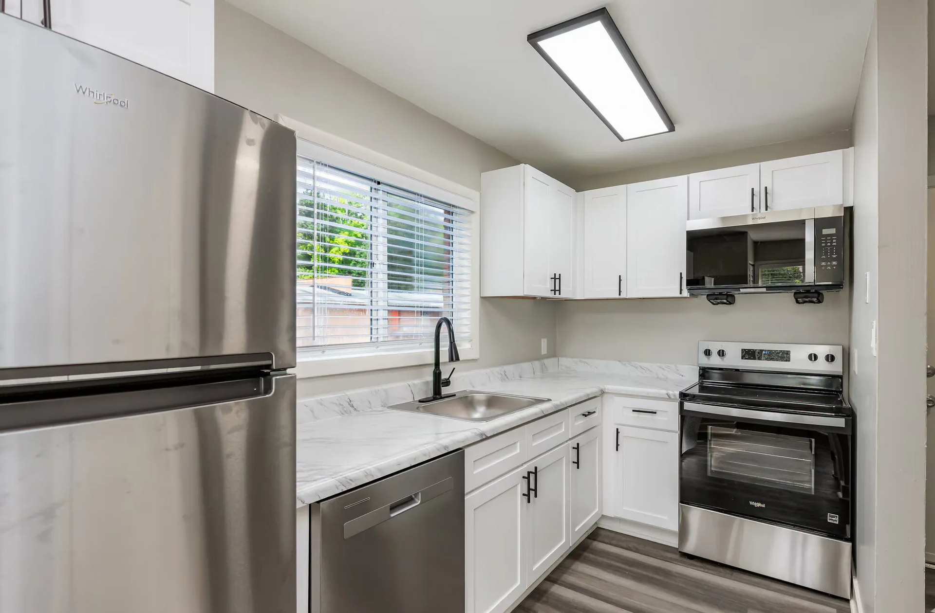 Compact modern kitchen with dark cabinets, black appliances, and light countertops on gray flooring
