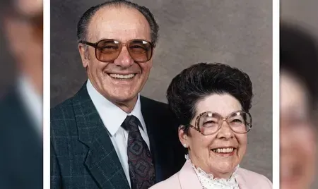 Smiling couple posing for a portrait, wearing glasses and formal clothing