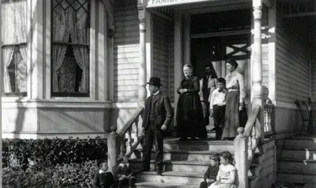 Several people stand on the steps of a house with Victorian-style trim.
