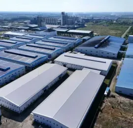 Aerial view of a large industrial complex with rows of blue-roofed warehouses and surrounding roads.