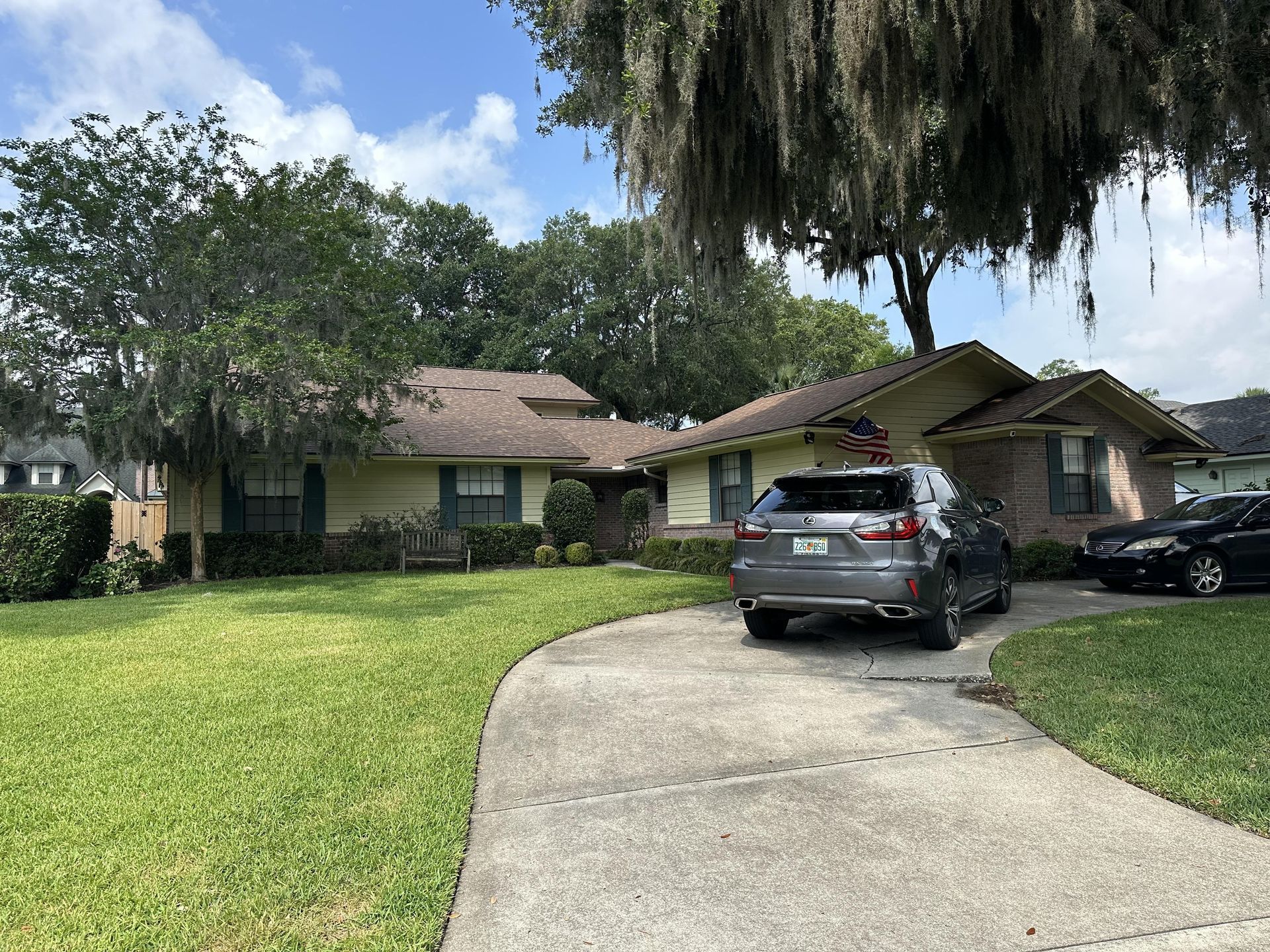 Suburban house with two cars in the driveway and a curved concrete path leading to the home