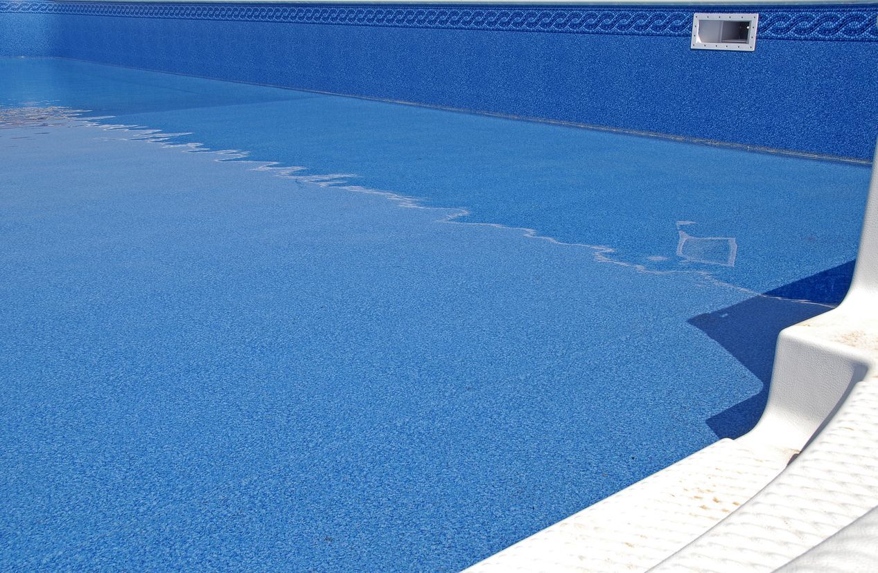 Blue swimming pool with a curved white edge and a tiled wall background