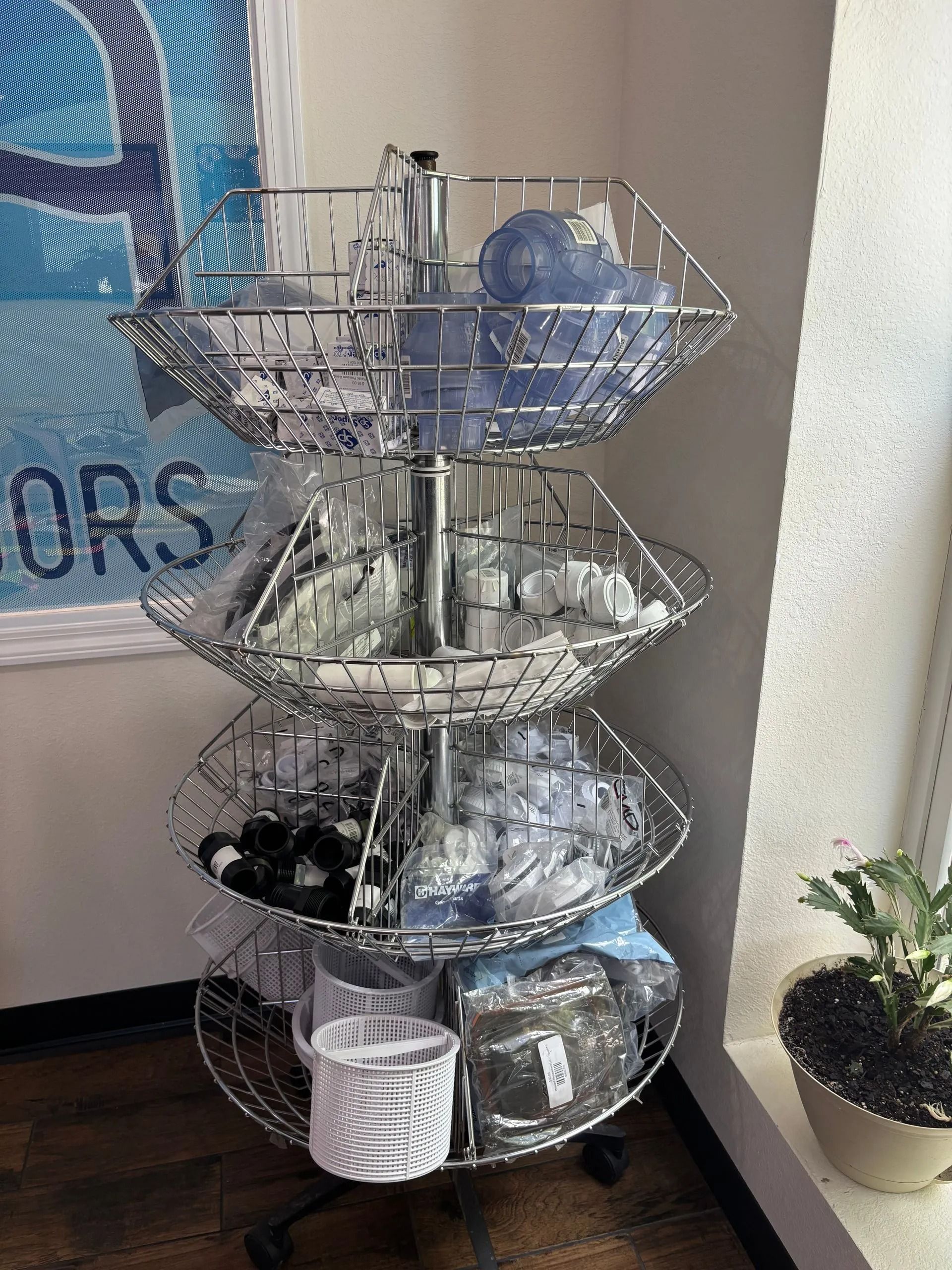 Metal wire display rack with blue and white bowls, next to a wall and potted plant.