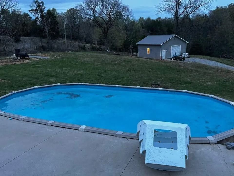Backyard swimming pool at dusk with a small shed and lawn in the background