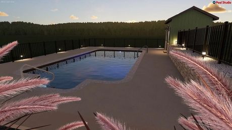 Backyard pool at dusk with pink flowers, a covered patio, and surrounding fence