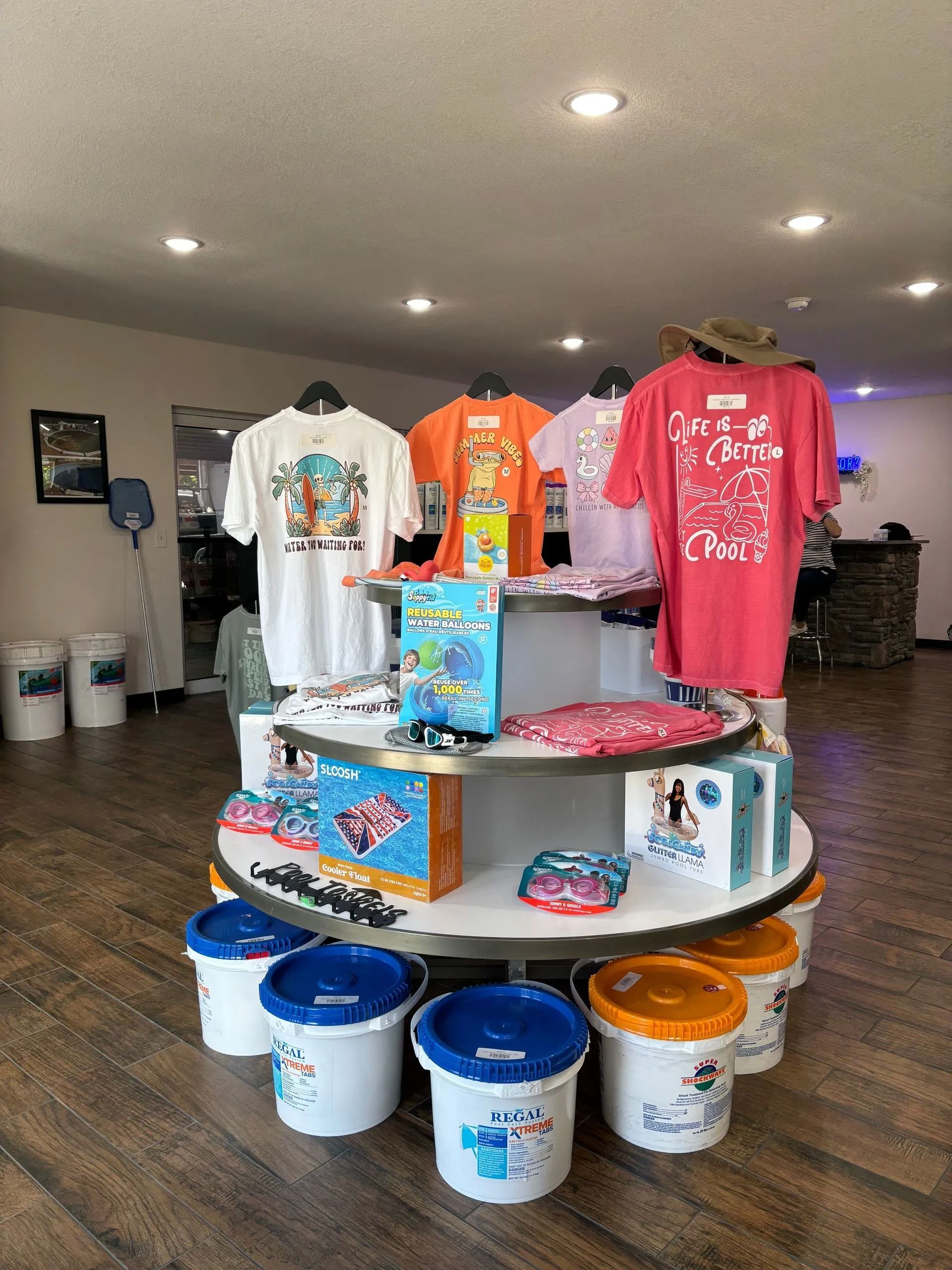 T-shirt and cup display on a round rack inside a brightly lit retail shop